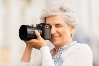Das Bild zeigt eine Frau mit Kamera in der Hand. 
