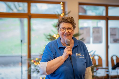 Hannelore Gruszczynski bei einer Veranstaltung, sie h&auml;lt ein Mikrofon in der Hand. Im Hintergrund sieht man einen Weihnachtsbaum.