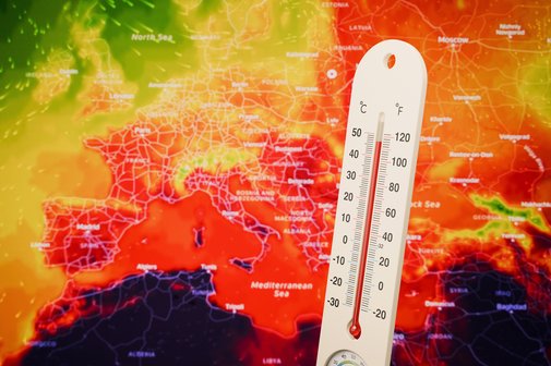 Die Bildmontage zeigt ein Thermometer, das eine extrem hohe Temperatur anzeigt vor einer Karte von Europa die &uuml;berwiegend rot eingef&auml;rbt ist als Hinweis auf hei&szlig;es Wetter.