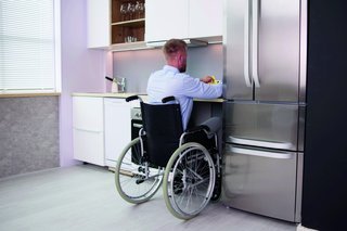 Mann im Rollstuhl in barrierefreier Küche.