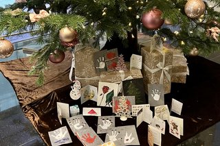 Auf dem Foto sind gebastelte Pinselpostkarten unter einem Weihnachtsbaum zu sehen.
