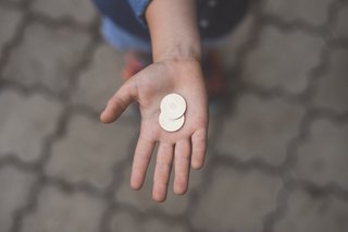 Auf dem Foto ist eine Hand zu sehen. In der Handfläche liegen Münzen. 