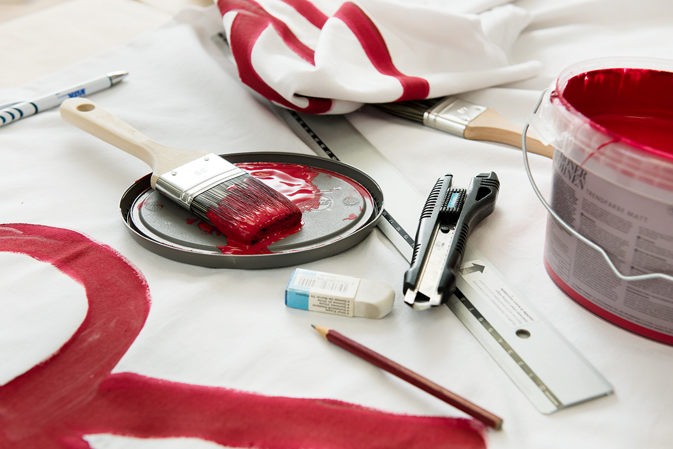 Demopappe Eine Demopappe, daneben rote Farbe und Pinsel.