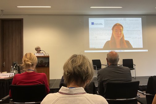 Zuhörer in der Konferenz Im Versammlungsraum sitzen Zuhörer und schauen auf die Rednerin und auf die Leinwand