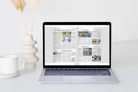 Laptop auf einem wei&szlig;en Tisch mit ge&ouml;ffneter digitaler Ausgabe der VdK-Zeitung Berlin-Brandenburg, daneben wei&szlig;e Tasse und wei&szlig;e Vase mit getrockneten Pflanzen.