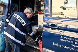 Ein Mitarbeiter der Berliner Stadtmissiongibt Sachen an Bedürftige