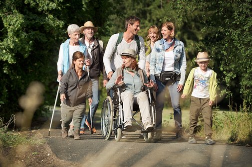 Eine Gruppe von VdK-Mitgliedern - M&auml;nner und Frauen, mit und ohne Behinderung - ist gemeinsam drau&szlig;en unterwegs wie bei einer Wanderung. Sie unterhalten sich.